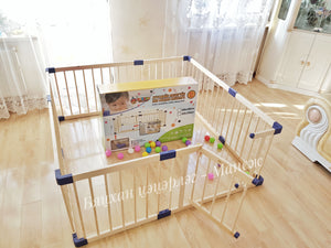 Wooden playpen with colorful balls and a toy box on a wooden floor.