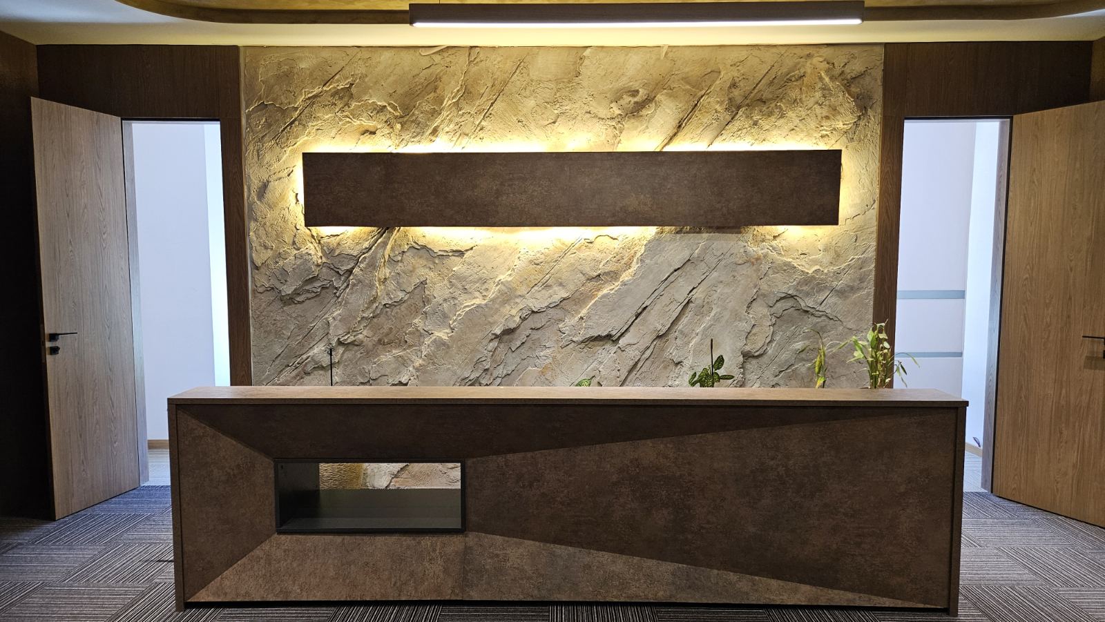 Modern office reception desk with stone wall and lighting fixture