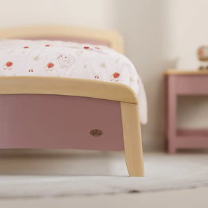 Children's bed with floral bedding and a nightstand in a room setting