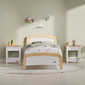 Children's bedroom with a wooden bed, white nightstands, and decorative items on a light green wall.
