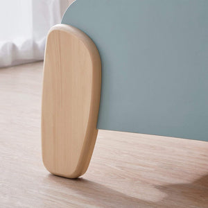 Close-up of a wooden footboard on a bed with a light blue headboard.
