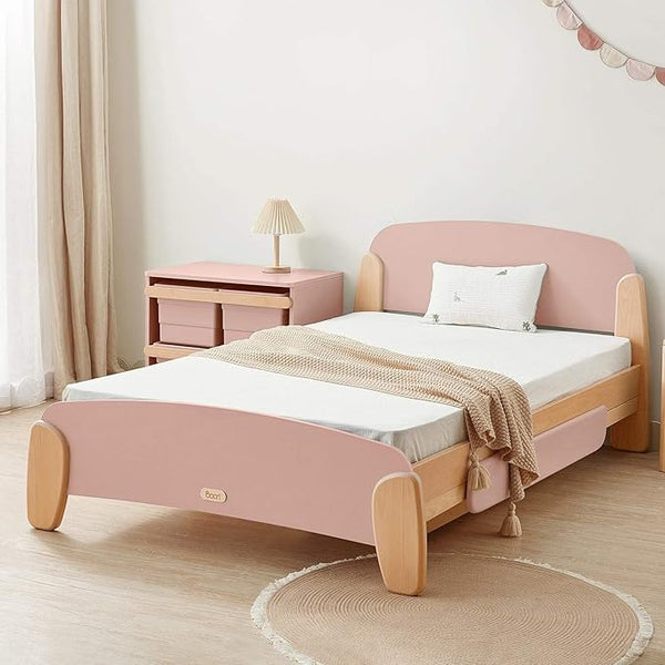 Pink and wooden bed in a room with a lamp and side table.