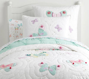 Children's bed with butterfly-themed bedding and pillows.