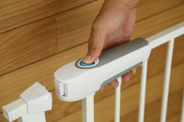 Hand pressing a button on a baby gate with a wooden background