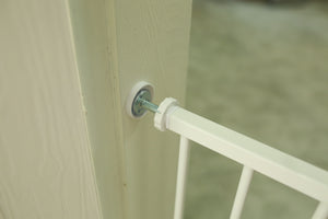 White baby gate attached to a wooden door with a blurred background