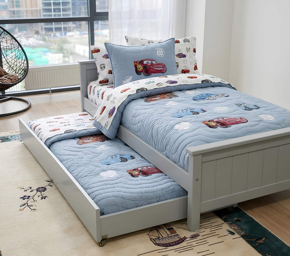 White bed with floral bedding in a room with curtains and a radiator.