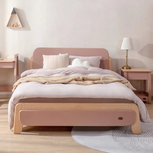 Wooden bed with pink headboard and footboard in a bedroom setting.