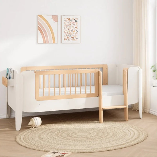 Wooden crib in a room with a round rug and wall art