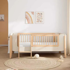 Wooden crib in a room with a white wall, round rug, and toys.