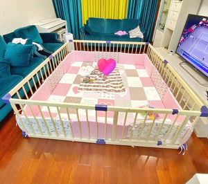 Baby crib with pink and white checkered sheet in a living room.