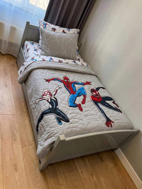 Children's bed with Spider-Man themed bedding in a room with light-colored walls and wooden floor.