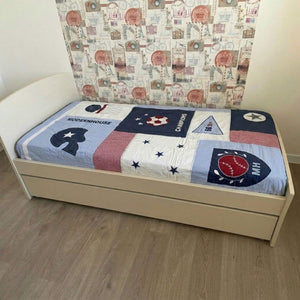 Beige bed with a colorful patchwork quilt against a patterned headboard.