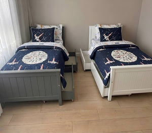 Two twin beds with Star Wars-themed bedding in a room with beige walls and wooden flooring.