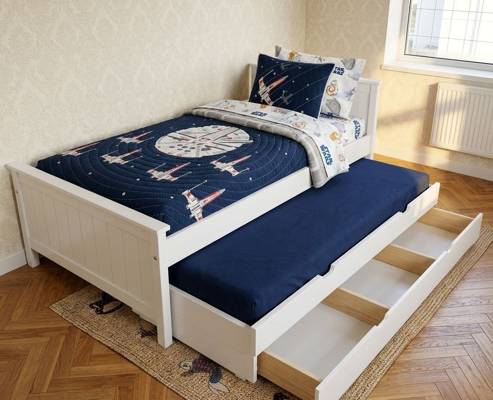 Children's bed with starship design bedding and pull-out trundle in a room.