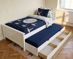 Children's bed with starship design bedding and pull-out trundle in a room.