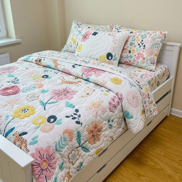 Floral quilt and pillow set on a bed in a room with wooden flooring.