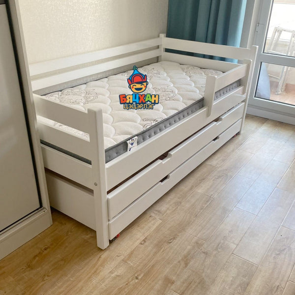 White children's bed with drawers on a wooden floor, featuring a visible brand logo.