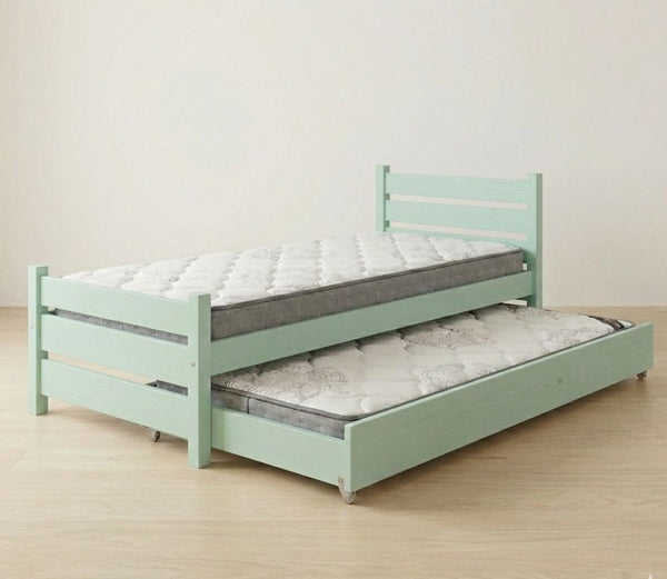 Light green bed with a mattress and pull-out trundle on a wooden floor.