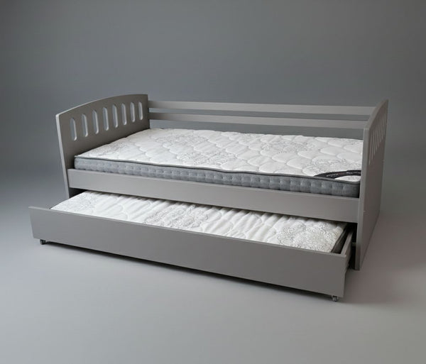 Gray bed frame with a mattress and pull-out trundle on a gray background
