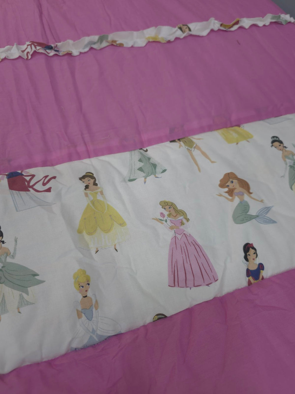 Children's bedroom with a pink and white floral bedspread on a wooden bed.
