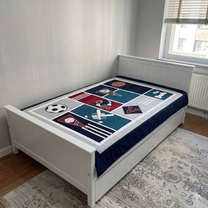 Bed with a sports-themed bedspread in a room with a window and radiator.