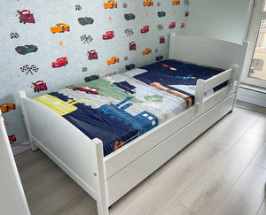 Children's bed with colorful bedding in a room with toy car wall decals.