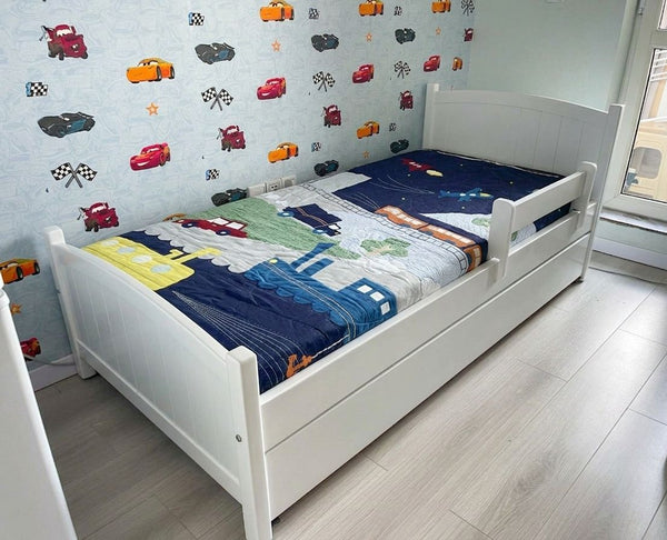 Children's bed with colorful bedding in a room with toy car wall decals.