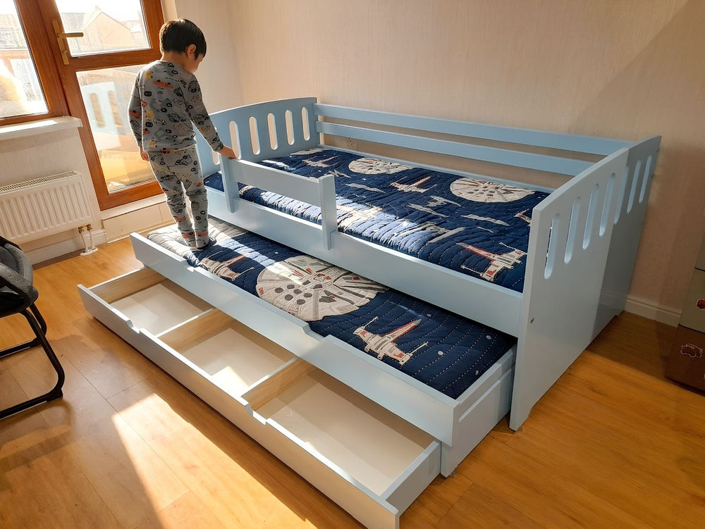 Children's bed with Star Wars bedding in a room with curtains and wooden floor.
