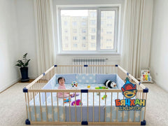 Child in a crib with toys in a room with a window and plant