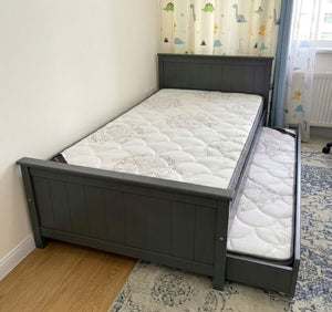 Gray bed frame with two mattresses in a room with a colorful curtain. Хүүхдийн ор, Классик загвар