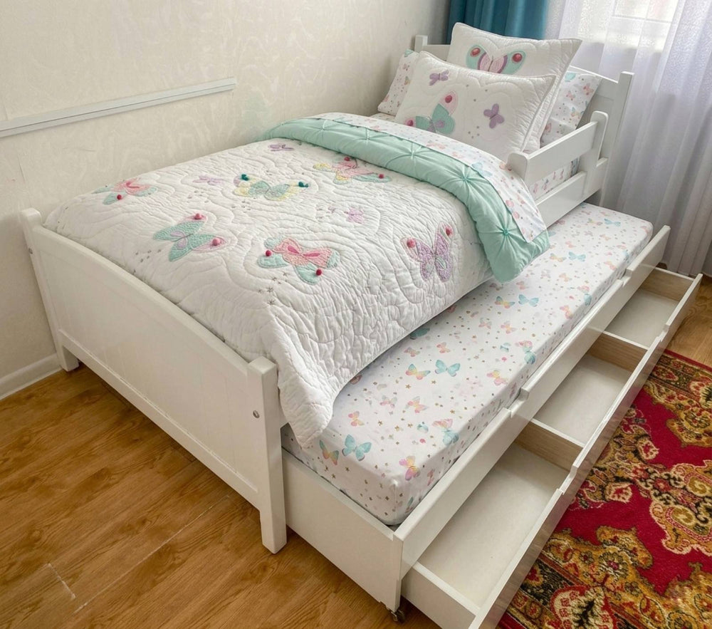 Pink children's bed with floral bedding and pillows in a room setting.