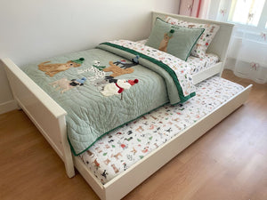 Children's bed with animal-themed bedding and pillows in a room.