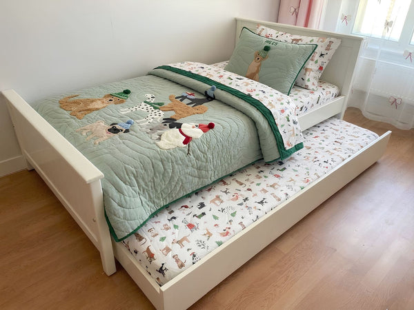 Children's bed with animal-themed bedding and pillows in a room.