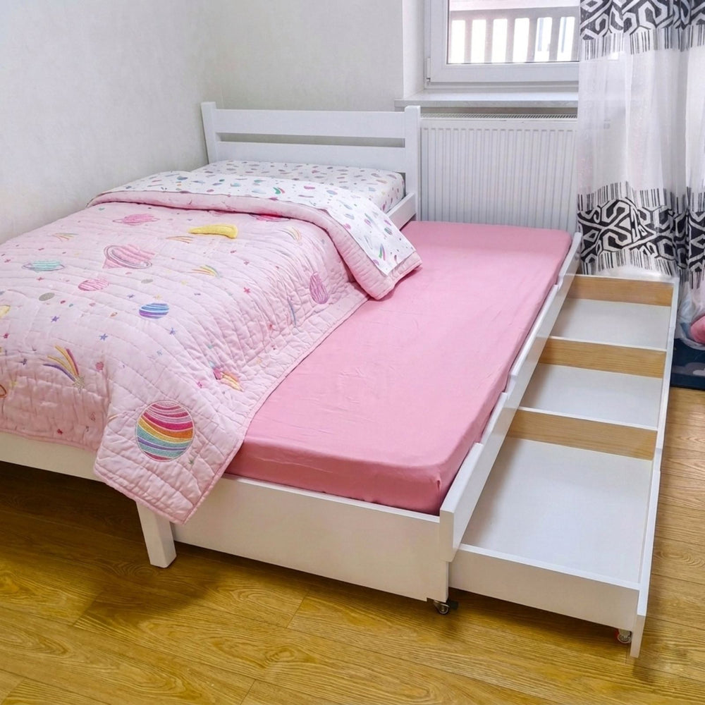 Children's bedroom with a bed featuring a dinosaur-themed quilt and pillows.