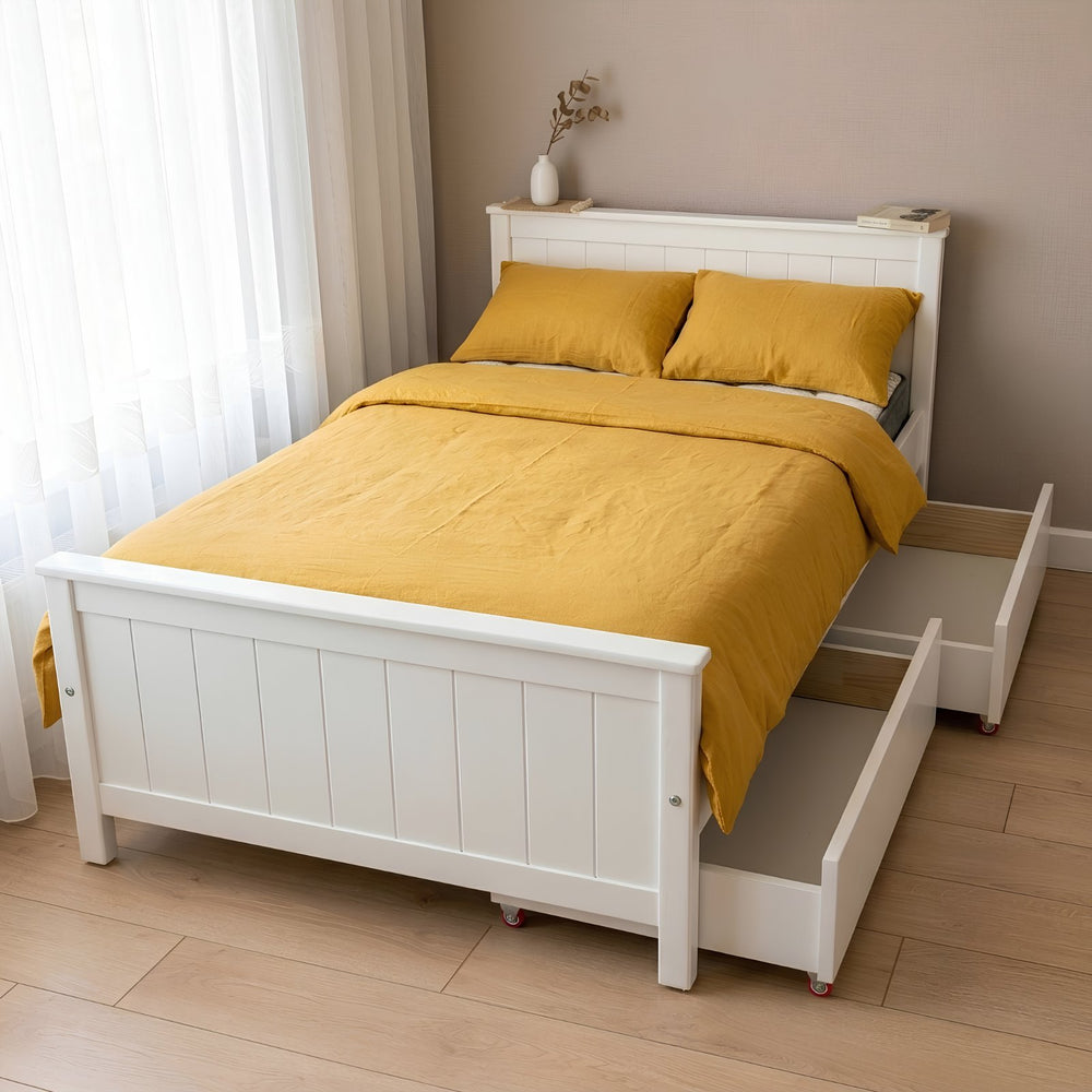 White bed with yellow bedding in a room with light wood flooring and white curtains.
