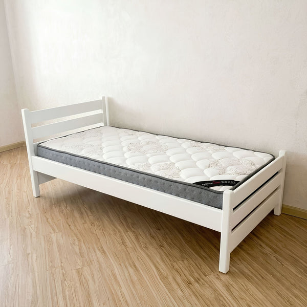 White bed frame with mattress on a wooden floor
